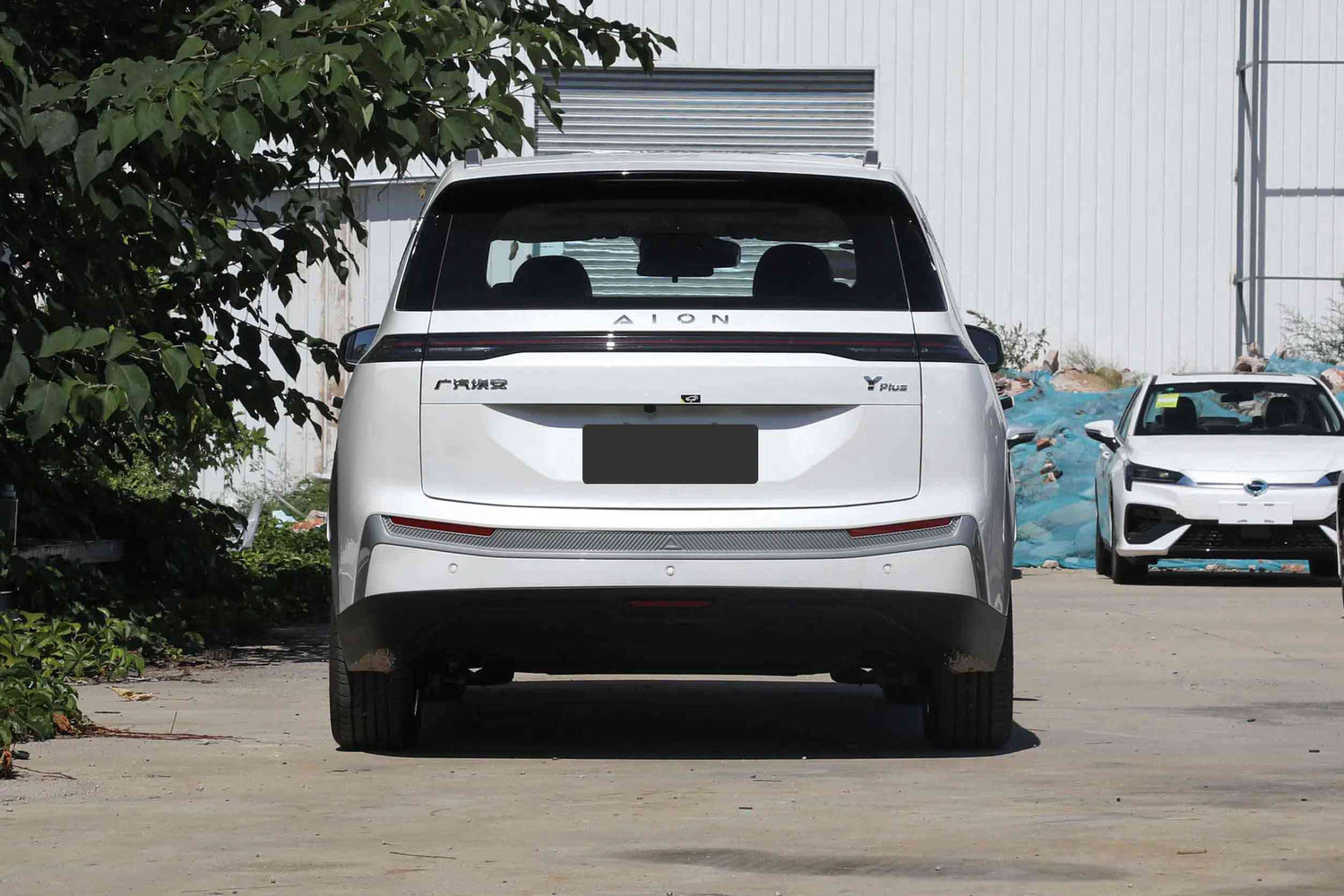 SUV GAC Aion Y Plus отзад, паркиран пред модерна сграда, подчертаващ футуристичен дизайн.