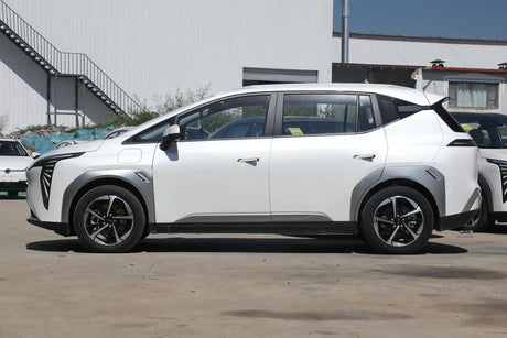 SUV GAC Aion Y Plus в профил, паркиран пред модерна сграда, подчертаващ футуристичен дизайн.