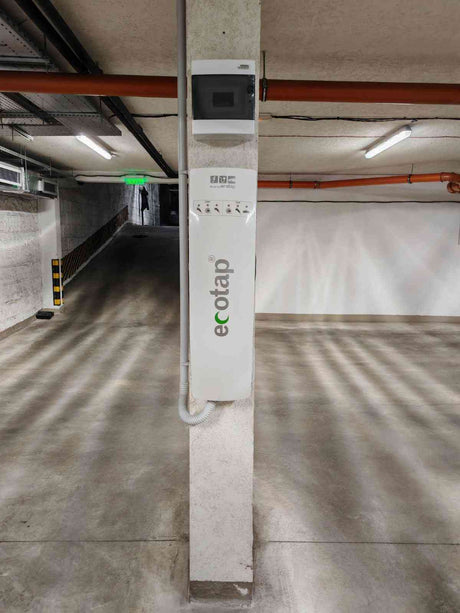 Ecotap Duo WallCharger 22kW монтирана на стълб в гараж, с централизирано електрическо табло за управление на зареждането.