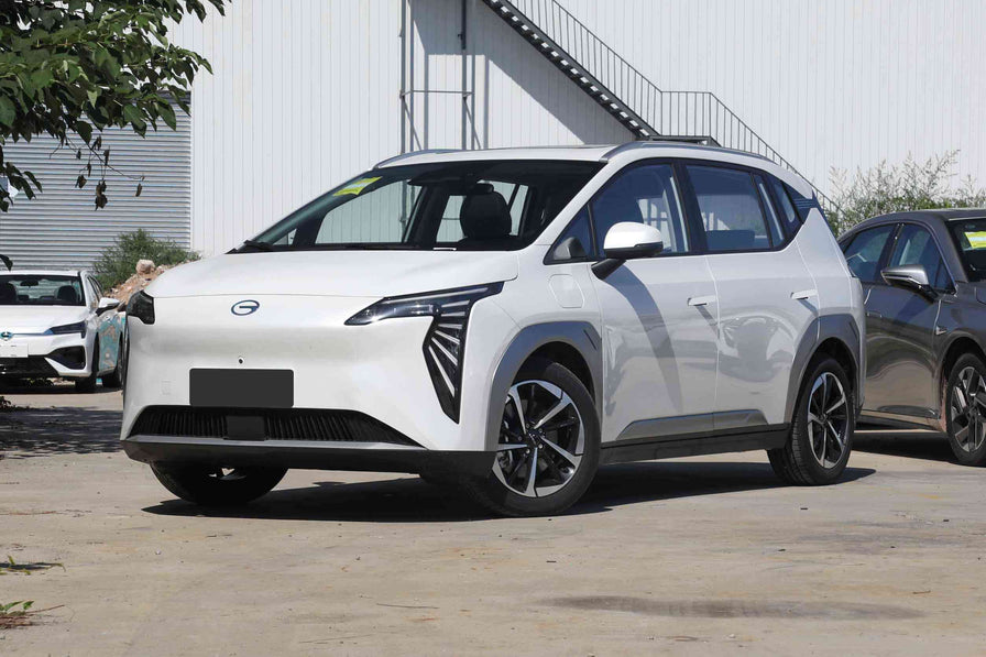 SUV GAC Aion Y Plus в бял цвят, паркиран пред модерна сграда, подчертаващ футуристичен дизайн.